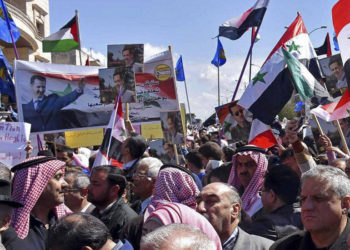 En esta foto publicada por la agencia de noticias oficial siria SANA, los sirios sostienen banderas nacionales y retratos del presidente sirio Bashar Assad durante una protesta contra el movimiento del presidente de Estados Unidos Donald Trump para reconocer la soberanía israelí sobre los Altos del Golán, en Homs, Siria, el 26 de marzo. 2019. (SANA via AP)
