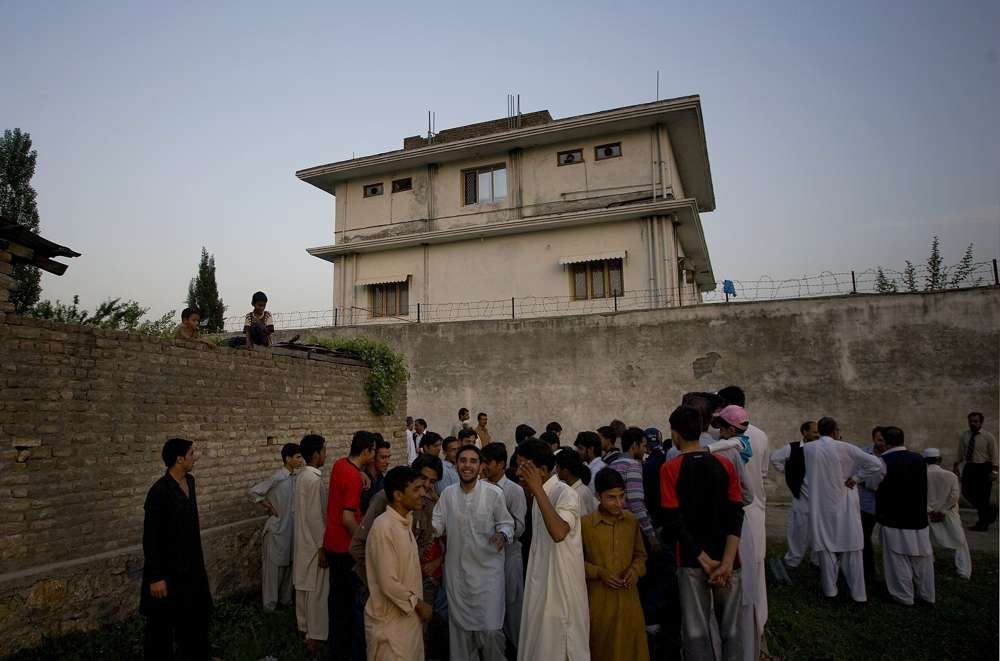 En esta foto de archivo del 3 de mayo de 2011, los residentes locales se reúnen fuera de una casa donde el líder de al-Qaeda, Osama bin Laden, fue asesinado en Abbottabad, Pakistán. (Foto AP / BKBangash, Archivo)