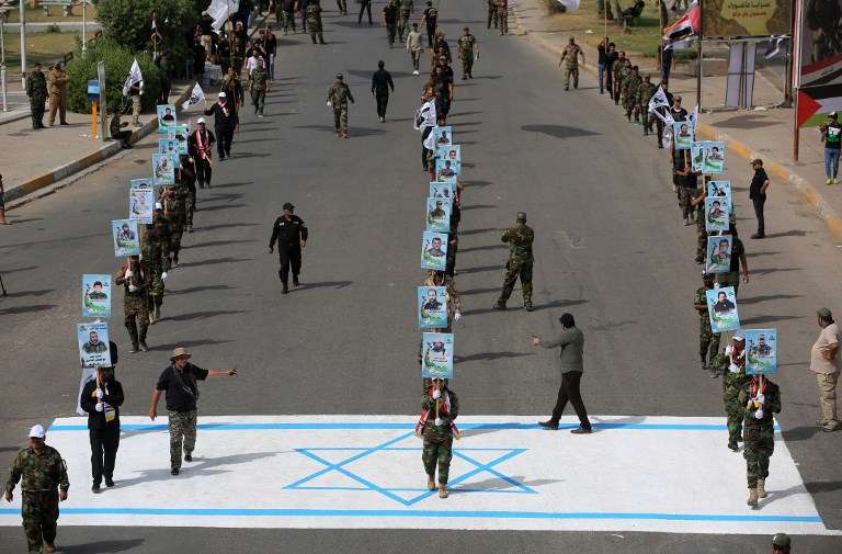 Los combatientes paramilitares chiítas aliados de Irán pisan una bandera israelí dibujada en la acera durante un mitin para conmemorar el “Día de Quds” iniciado por Irán en 1979 para caer el último viernes del mes sagrado del Ramadán, en el Iraq. la capital, Bagdad, el 8 de junio de 2018. (AFP / Ahmad al-Rubaye)