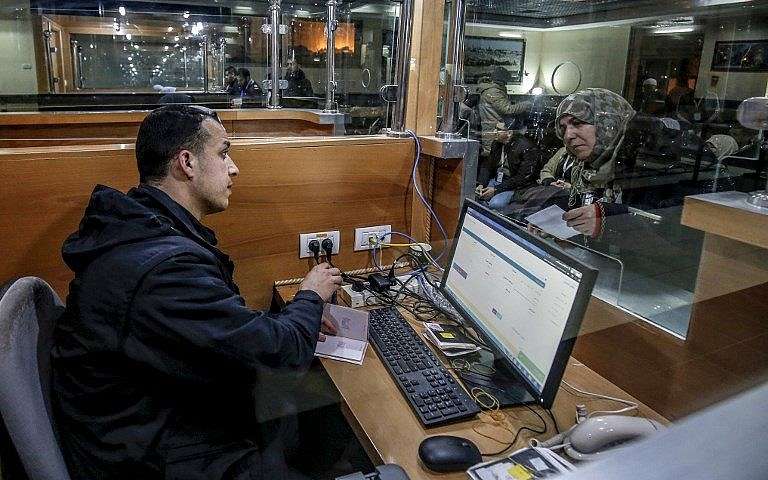 Un oficial de control fronterizo de Hamás verifica los documentos de viaje de una peregrina musulmana que espera en el cruce fronterizo de Rafah entre la Franja de Gaza y Egipto el 3 de marzo de 2019, antes de cruzar para partir hacia la ciudad sagrada musulmana de La Meca para realizar el peregrinaje ritual de Umra por primera vez desde 2014. (Said Khatib / AFP)