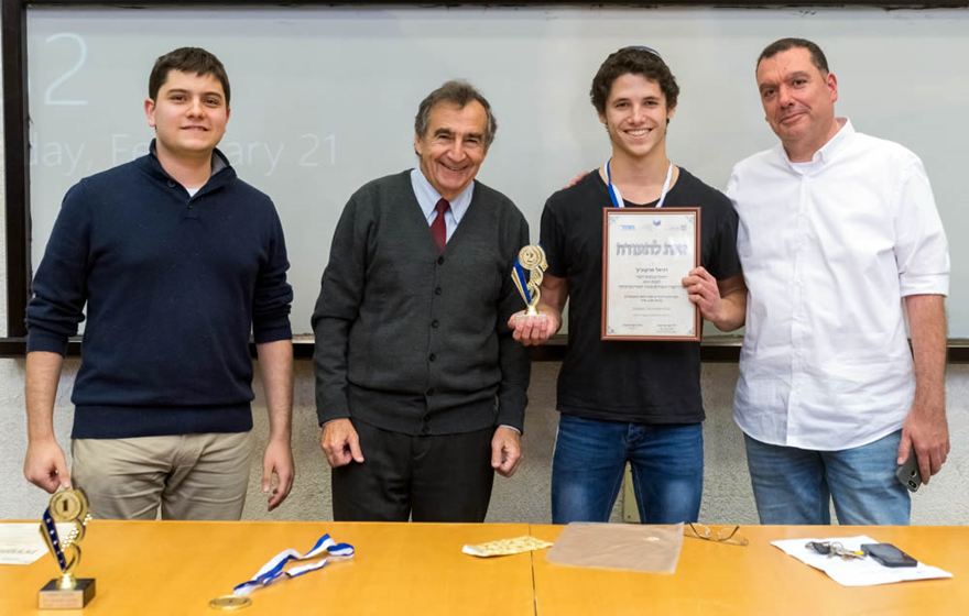 Daniel Markovitz de Netanya, flanqueado por el director de la Olimpiada Evgeny Frishman a su izquierda y el instructor Yitzhak Gvili a su derecha. Crédito: JCT.