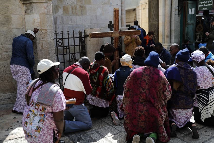 Los fieles se arrodillan para orar frente a una cruz de madera a lo largo de la Vía Dolorosa en la Ciudad Vieja de Jerusalén durante la procesión del Viernes Santo el 19 de abril de 2019. (Thomas Coex / AFP)