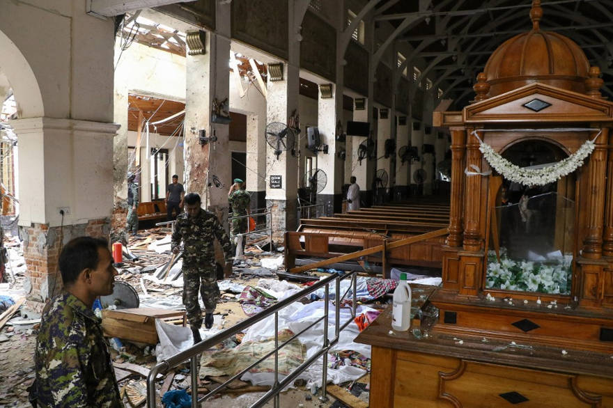 El personal de seguridad de Sri Lanka pasa junto a cadáveres cubiertos con mantas en medio de una explosión en el Santuario de San Antonio después de una explosión en la iglesia de Colombo el 21 de abril de 2019. (ISHARA S. KODIKARA / AFP)