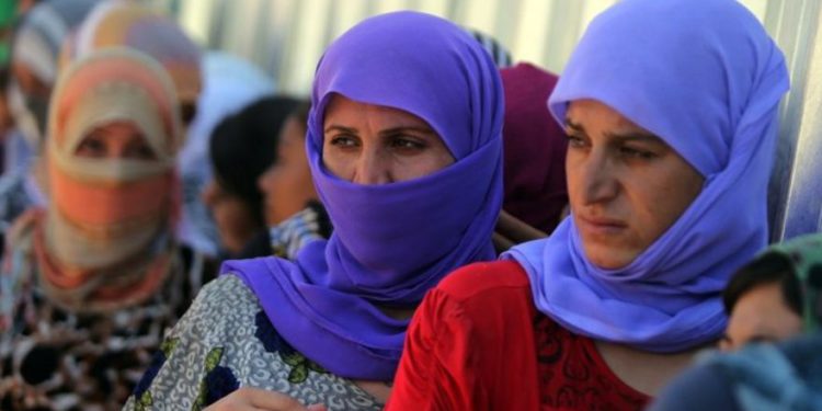 Las mujeres iraquíes de Yazidi hacen cola para obtener comida en el campamento de Bajid Kandala, cerca del río Tigris, en la provincia de Dohuk, en el occidente de Kurdistán, donde se refugiaron tras huir de los avances de los jihadistas del Estado Islámico en Irak el 13 de agosto de 2014. Crédito de la foto: AFP / AHMAD AL-RUBAYE)