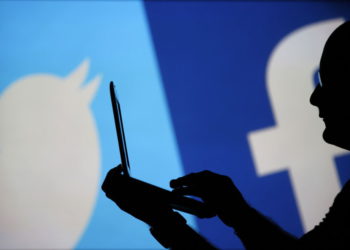 Un hombre está recortado contra una pantalla de video con un Twitter y un logotipo de Facebook. (Crédito de la foto: DADO RUVIC / REUTERS)