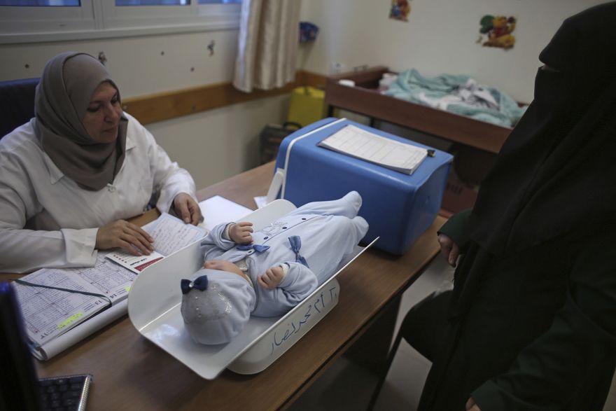 En esta foto del 14 de enero de 2018, una mujer palestina hace controlar a su hijo en una clínica administrada por la UNRWA en el campamento de refugiados de Shati, ciudad de Gaza. (Foto AP / Khalil Hamra)