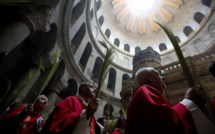 Los sacerdotes católicos llevan hojas de palma en la Iglesia del Santo Sepulcro, tradicionalmente muchos cristianos creían que era el lugar de la crucifixión y el entierro de Jesús en la Ciudad Vieja de Jerusalén, el 14 de abril de 2019. (AP Photo / Sebastian Scheiner)