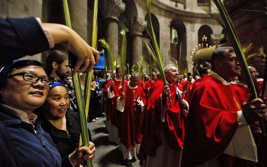 Los sacerdotes católicos llevan hojas de palma en la Iglesia del Santo Sepulcro, tradicionalmente muchos cristianos creían que era el lugar de la crucifixión y el entierro de Jesús en la Ciudad Vieja de Jerusalén, el 14 de abril de 2019. (AP Photo / Sebastian Scheiner)