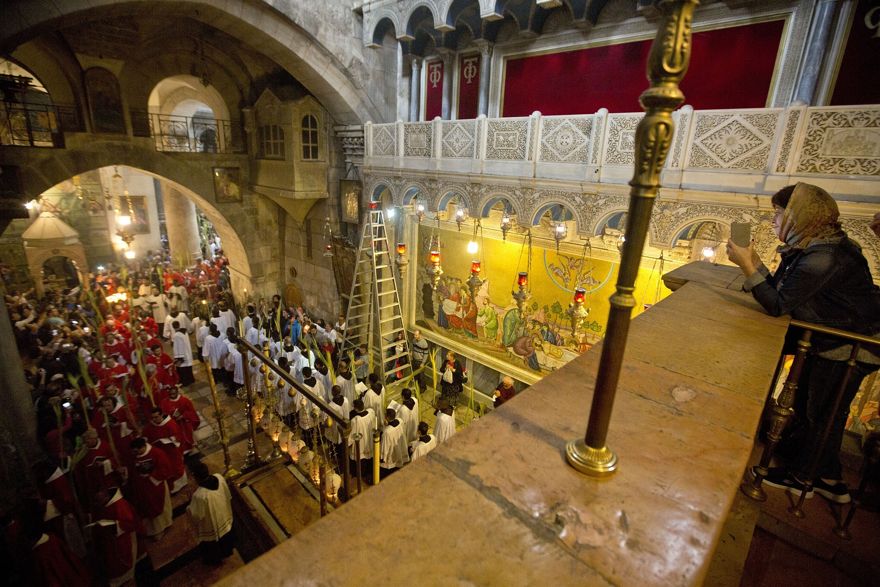Un peregrino cristiano mira cómo los sacerdotes católicos llevan hojas de palma en la Iglesia del Santo Sepulcro, tradicionalmente muchos cristianos creían que era el lugar de la crucifixión y el entierro de Jesús, en la Ciudad Vieja de Jerusalén, el 14 de abril de 2019. (Foto AP / Sebastian Scheiner)