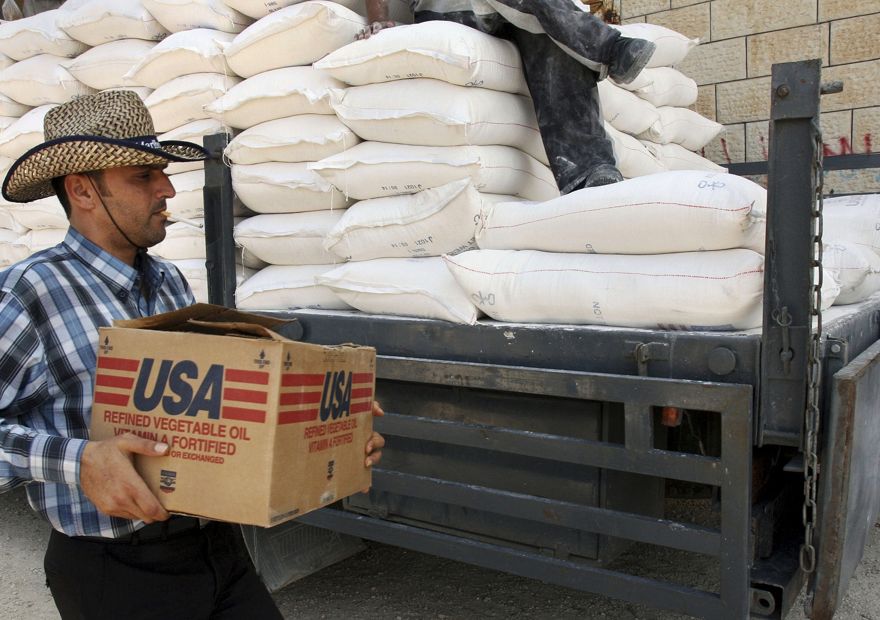 Un palestino lleva una caja de aceite vegetal mientras camina sobre bolsas de harina en un camión donado por USAID, o la Agencia de los Estados Unidos para el Desarrollo Internacional, en un depósito en la aldea de Anin, cerca de Jenin, 4 de junio de 2008 (AP Foto / Mohammed Ballas)