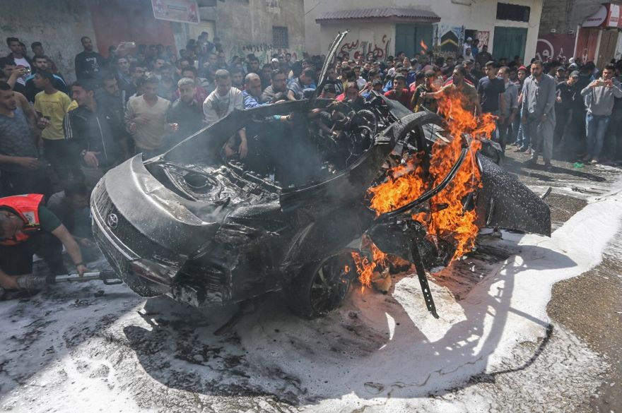 El personal de emergencia palestino intenta apagar el fuego en un automóvil perteneciente al miembro principal del grupo terrorista Hamás, Hamed Hamdan al-Khodari, luego de que fue golpeado por un ataque aéreo israelí en la ciudad de Gaza el 5 de mayo de 2019. (MAHMUD HAMS / AFP)