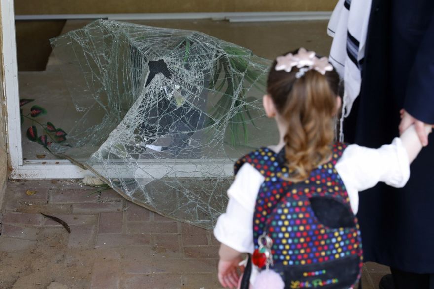 Una niña israelí, el 6 de mayo de 2019, mira vidrios rotos en la entrada de un edificio dañado por un ataque con cohetes desde la Franja de Gaza, en la ciudad de Ashdod, en el sur de Israel. (Jack Guez / AFP)