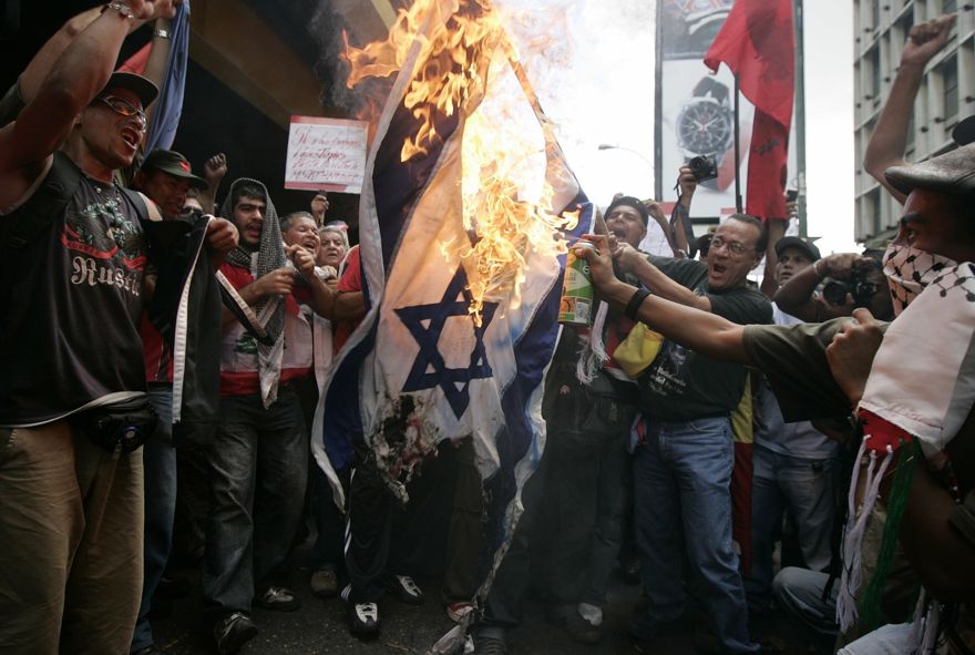 Los manifestantes quemaron una bandera israelí durante una protesta frente a la embajada de Israel en Caracas, el jueves 8 de enero de 2009. Los manifestantes que condenaban la ofensiva de Israel en la Franja de Gaza salpicaron graffiti y arrojaron zapatos en la embajada del país en Venezuela el jueves, respaldando la decisión del presidente Hugo Chávez de expulsar El embajador israelí. (Foto AP / Fernando Llano)