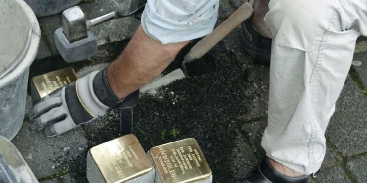 El artista Gunter Demnig coloca Stolpersteine, pequeñas placas de bronce que conmemoran a las víctimas de los nazis, en Colonia en 2015. (Crédito de la foto: KARIN RICHERT)