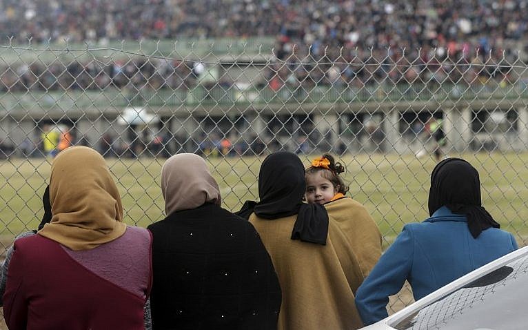 Mujeres palestinas miran el partido de fútbol entre Al-Nuseirat y Al-Jalaa, de pie frente a la valla del estadio en el campamento de refugiados de Nuseirat, al sur de la ciudad de Gaza, el 28 de enero de 2018. (AFP PHOTO / MAHMUD JAMS)