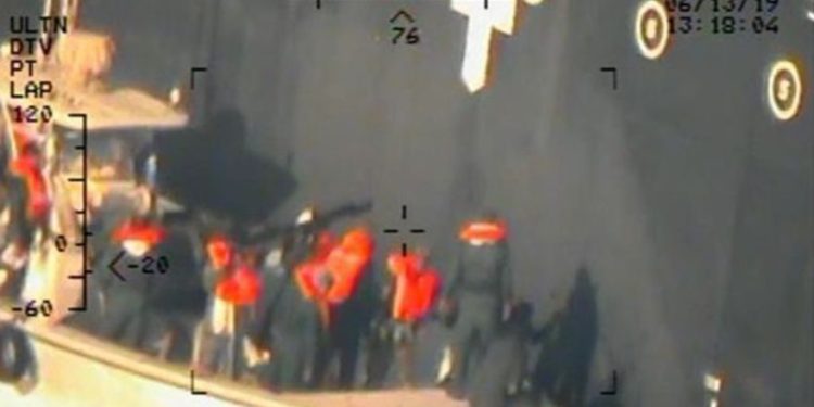Esta imagen, publicada por el Departamento de Defensa de los EE. UU. El lunes 17 de junio de 2019 y tomada de un helicóptero de la Armada de los EE. UU., Muestra lo que la Armada dice que son miembros del Cuerpo de la Guardia Revolucionaria Islámica, que están retirando una mina de laca sin explotar del M / T Kokuka. Valiente. (Departamento de Defensa de los Estados Unidos a través de AP)
