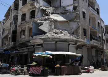 ARCHIVO - La gente pasa frente a un edificio dañado en la ciudad de Idlib, Siria, el 25 de mayo de 2019.