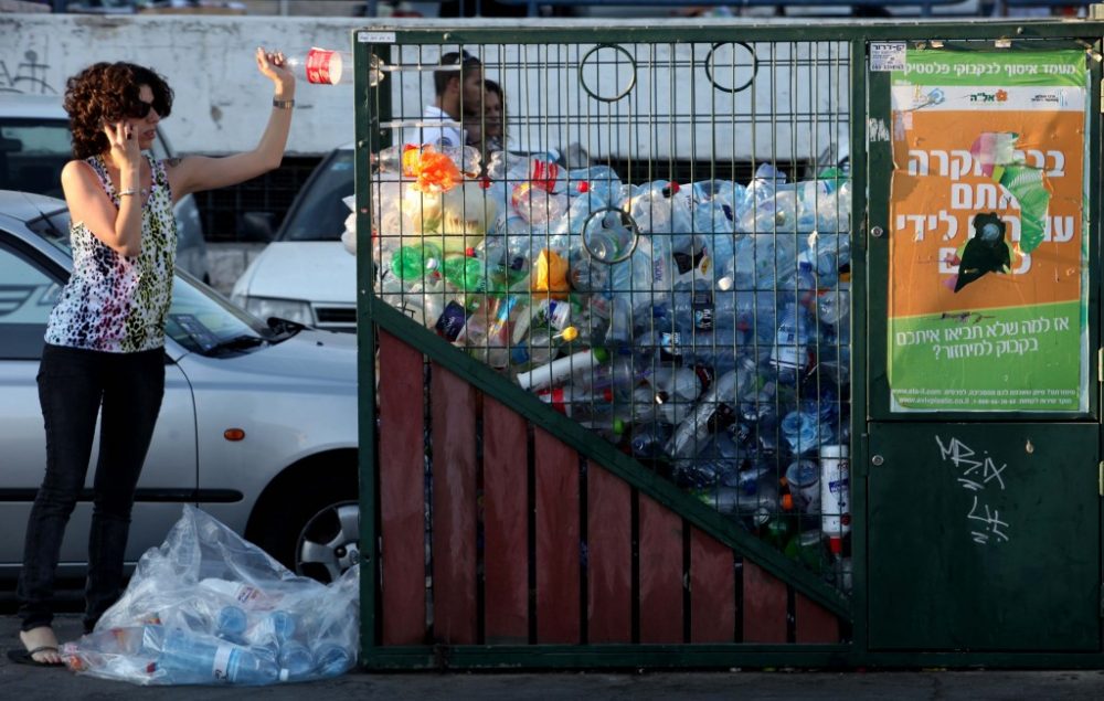 Una mujer tira una botella al contenedor de reciclaje en el centro de Jerusalén. (Crédito de la foto: Nati Shohat / Flash90)