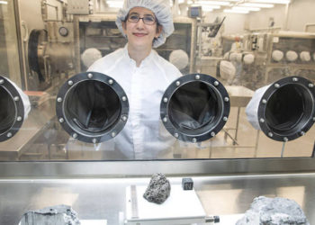 La reportera de astronomía Science News Lisa Grossman visita el prístino laboratorio de muestras en el Centro Espacial Johnson de la NASA en Houston en marzo. La vitrina contiene rocas recolectadas durante el Apolo 15 y 16. El trozo de basalto volcánico de 1.5 kilogramos en el centro tiene 3.400 millones de años.