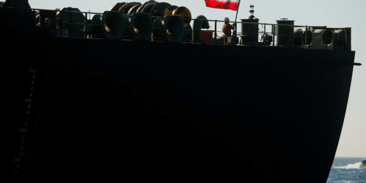 Un miembro de la tripulación levanta la bandera iraní en el petrolero iraní Adrian Darya 1, anteriormente llamado Grace 1, ya que se encuentra anclado después de que la Corte Suprema del territorio británico levantó su orden de detención, en el Estrecho de Gibraltar. (crédito de la foto: JON NAZCA / REUTERS)