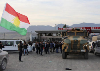 Un hombre agita una bandera de Kurdistán mientras un camión militar turco escolta a un convoy de vehículos peshmerga en la puerta fronteriza de Habur, que separa Turquía de Irak, cerca de la ciudad de Silopi, en el sureste de Turquía. (Crédito de la foto: REUTERS)