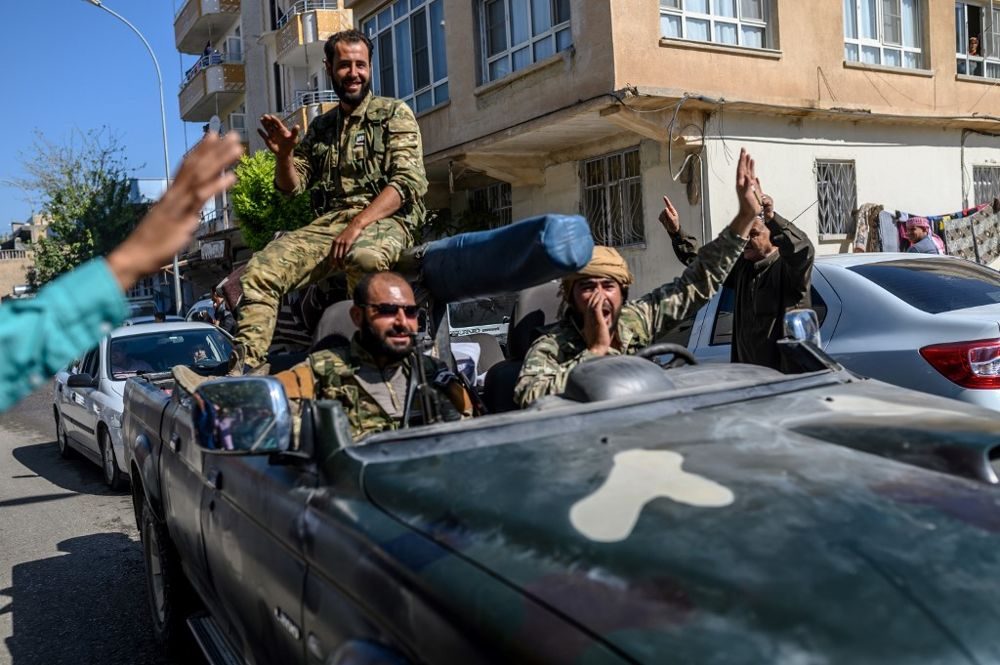 Los combatientes de la oposición siria respaldados por Turquía van a Tel Abyad desde la puerta turca hacia Siria en Akcakale en la provincia de Sanliurfa el 10 de octubre de 2019. (BULENT KILIC / AFP)