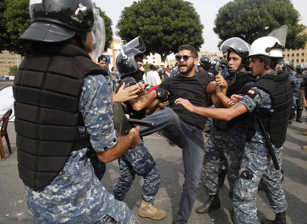 La policía retira a un manifestante antigubernamental que bloquea una carretera principal con su cuerpo en Beirut, Líbano, 26 de octubre de 2019 (Foto AP / Hussein Malla)