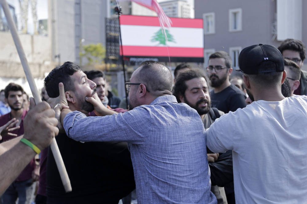 Los partidarios de Hezbolá, en primer plano, luchan con un manifestante antigubernamental durante los enfrentamientos que surgieron entre ellos durante las protestas en curso contra el gobierno libanés en Beirut, Líbano, 29 de octubre de 2019 (AP Photo / Hassan Ammar)