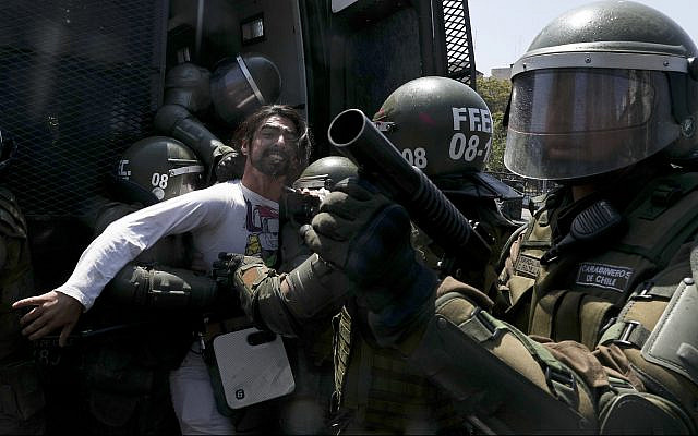 Un manifestante patea un bote de gas lacrimógeno durante los enfrentamientos con la policía en Santiago, Chile, 20 de octubre de 2019. (Foto AP / Esteban Felix)