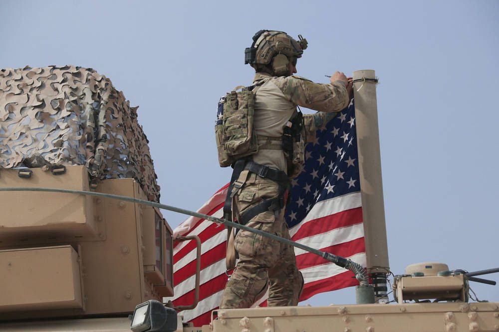 Soldado estadounidense monta la bandera estadounidense en un vehículo cerca de la ciudad de Tel Tamr, norte de Siria, el domingo 20 de octubre de 2019. (Foto AP / Baderkhan Ahmad)