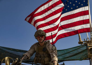 Un soldado se sienta encima de un vehículo militar estadounidense que pasa por la ciudad siria del noreste de Qahtaniyah, en la frontera con Turquía, el 31 de octubre de 2019 (Delil SOULEIMAN / AFP