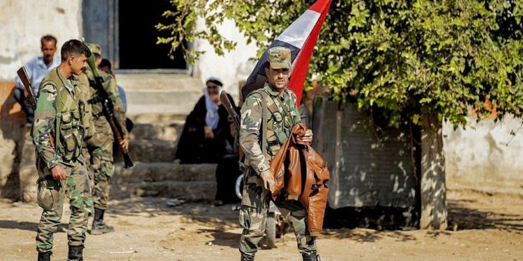 Las fuerzas del régimen sirio son representadas mientras patrullan una calle en la entrada occidental de la ciudad de Tal Tamr, en el campo de la provincia de Hasakeh, en el noreste de Siria, el 14 de octubre de 2019. (Delil Souleiman / AFP)