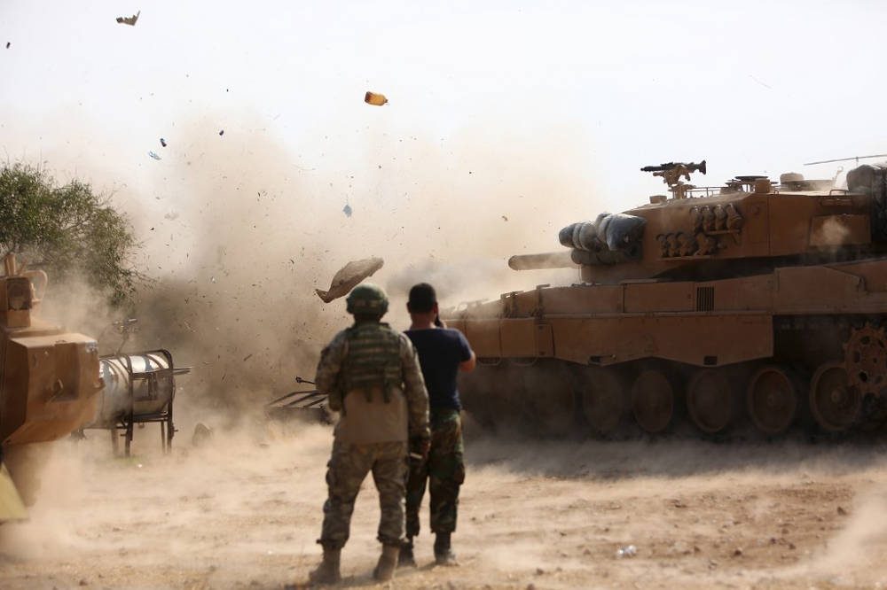 Soldados turcos en una posición al este de la ciudad siria nororiental de Ras al-AIn observan cómo un tanque dispara en las posiciones mantenidas por combatientes del Ejército Democrático Sirio (SDF) el 28 de octubre de 2019. (Nazeer Al-khatib / AFP)