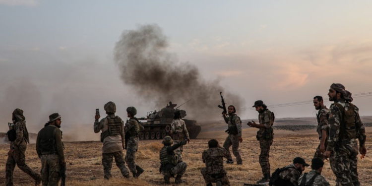 Soldados turcos y combatientes sirios respaldados por Turquía se reúnen en las afueras del norte de la ciudad siria de Manbij, cerca de la frontera turca, el 14 de octubre de 2019, mientras Turquía y sus aliados continúan atacando las ciudades fronterizas controladas por los kurdos en el noreste de Siria. (Zein Al Rifai / AFP)