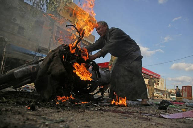 Un hombre sirio se encuentra junto a una motocicleta en llamas en el lugar de la explosión de un coche bomba en la ciudad kurda de Tal Abyad, en el norte de Siria, en la frontera con Turquía, el 2 de noviembre de 2019. (Bakr Alkasem / AFP)