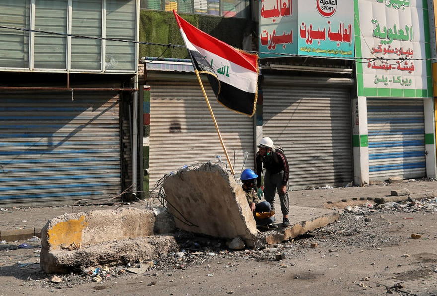 Los manifestantes antigubernamentales se refugian durante los enfrentamientos con las fuerzas de seguridad en la calle Rasheed, Bagdad, Irak, 26 de noviembre de 2019. (Foto AP / Khalid Mohammed)