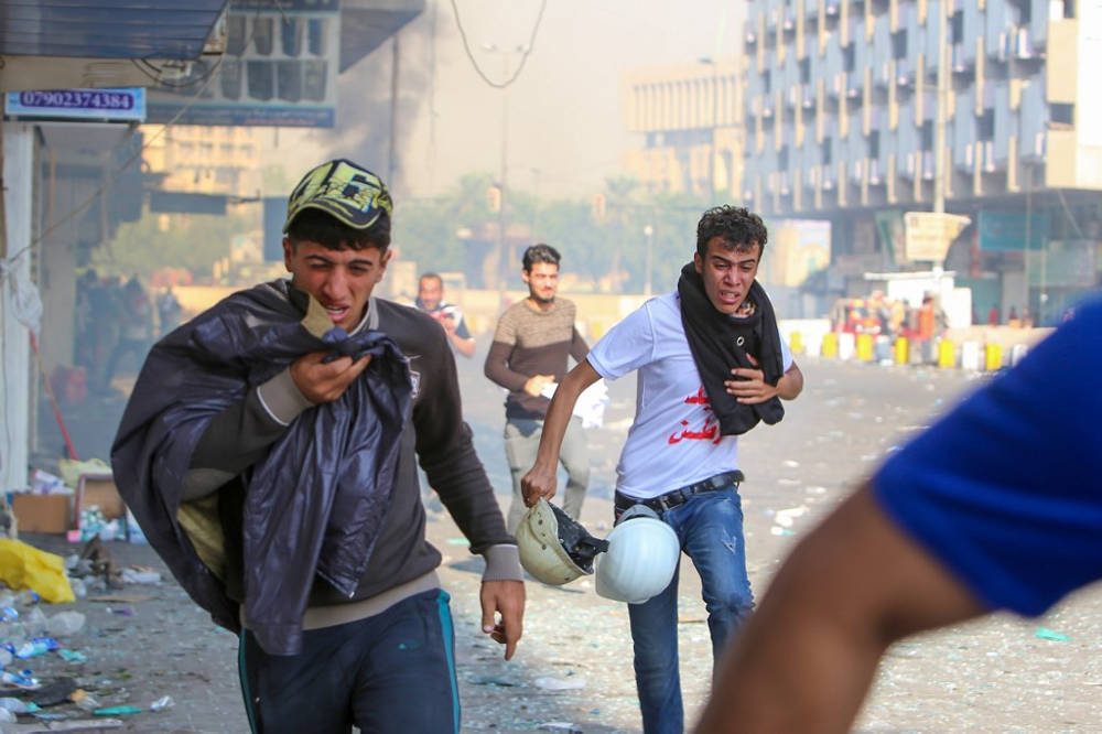 Los manifestantes iraquíes se refugian en gases lacrimógenos disparados por las fuerzas de seguridad en la plaza al-Khalani en el centro de Bagdad el 10 de noviembre de 2019. (Sabah Arar / AFP)