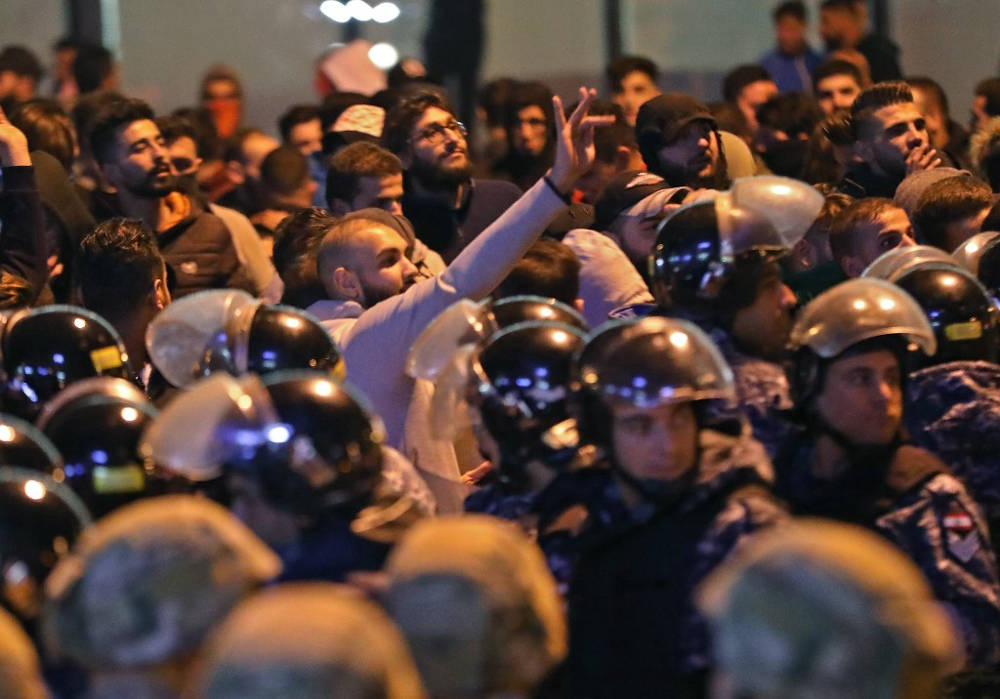 Un partidario de los movimientos libaneses de Hezbolá y Amal hace gestos con el dedo medio mientras los soldados del ejército y la policía antidisturbios se despliegan en medio de enfrentamientos con manifestantes antigubernamentales en la capital Beirut, el 25 de noviembre de 2019. (Foto de ANWAR AMRO / AFP)