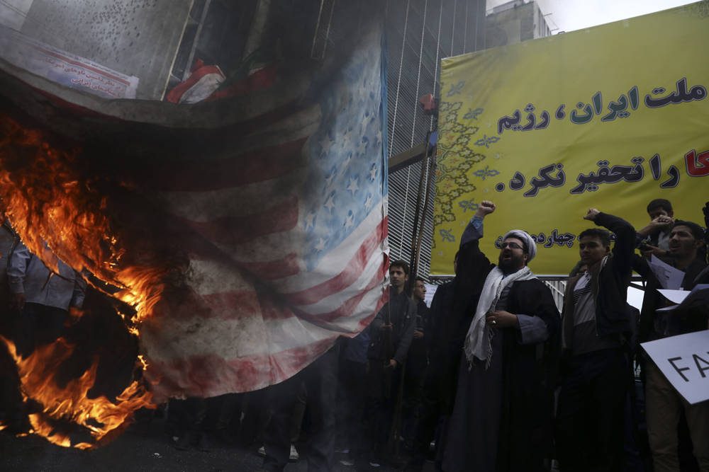 Los manifestantes iraníes cantan consignas mientras prendieron fuego a una bandera estadounidense improvisada durante una manifestación anual frente a la antigua Embajada de los Estados Unidos en Teherán, Irán, el 4 de noviembre de 2019 (AP Photo / Vahid Salemi)