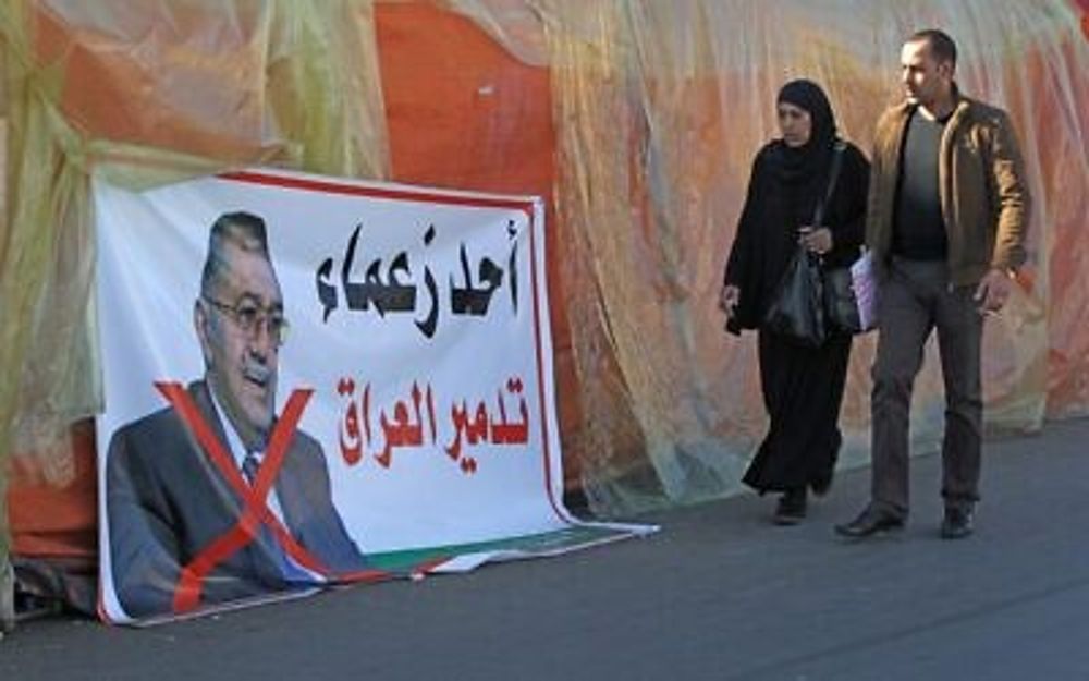 Los manifestantes iraquíes pasan junto a un cartel que rechaza al ministro saliente de educación superior Qusay al-Suhail como candidato potencial para primer ministro, en medio de las continuas protestas antigubernamentales en la plaza Tahrir en la capital Bagdad, 19 de diciembre de 2019. (Ahmad al-Rubaye / AFP)