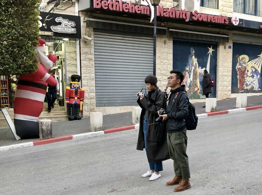 Una pareja de turistas toma fotos en una de las calles principales de Belén. Foto de Judy Lash Balint.