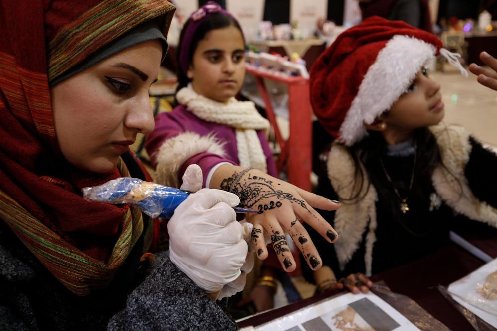 Una niña recibe un tatuaje de henna '2020' en una exhibición de artesanía tradicional de Gaza ( Foto: AFP )