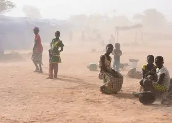 Las personas desplazadas, que huyeron de los ataques de militantes armados en Roffenega, se ven envueltas en polvo mientras se sientan en el campamento construido por la ayuda alemana Ngo HELP en Pissila (crédito de la foto: REUTERS)