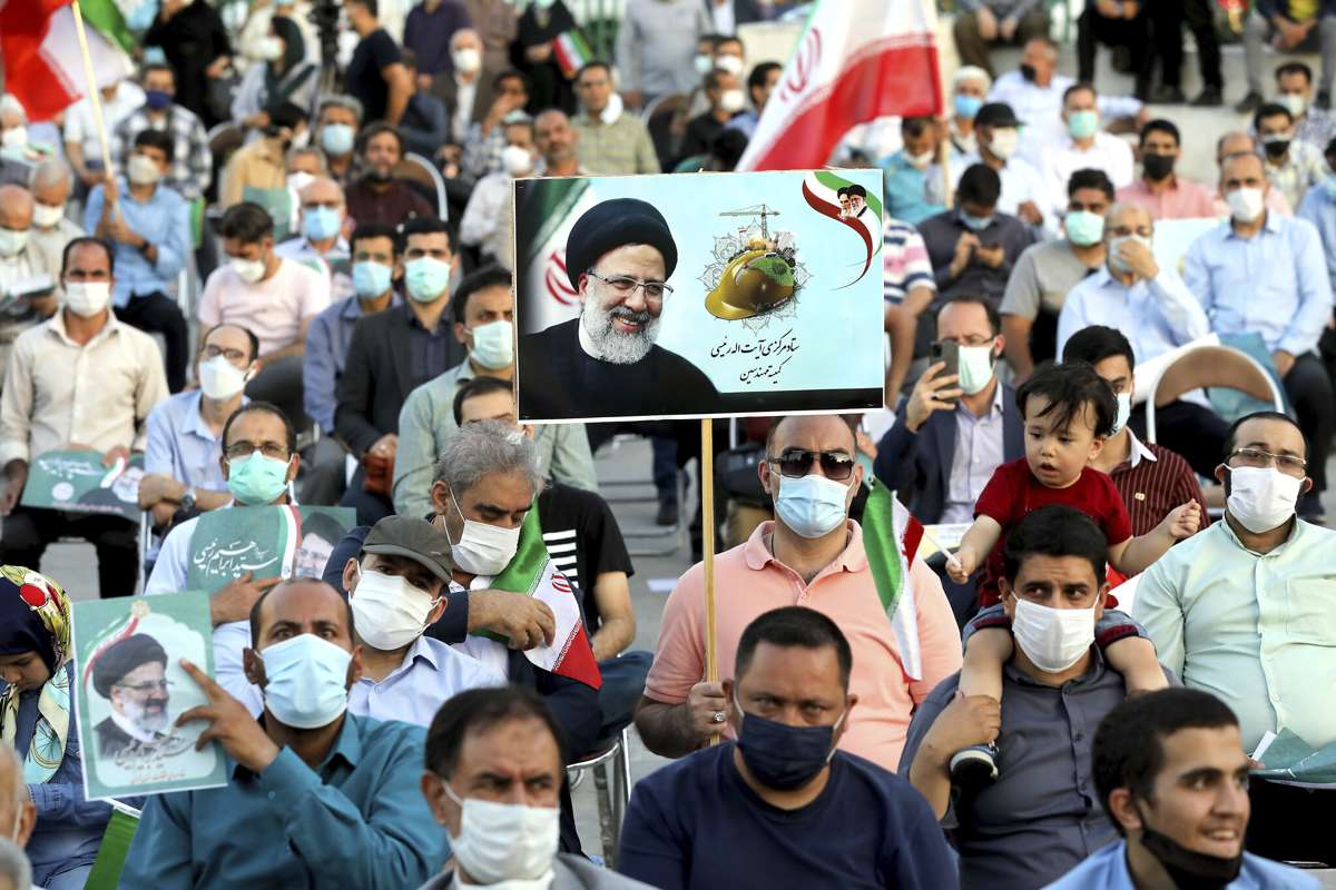 Simpatizantes del candidato presidencial Ebrahim Raisi sostienen carteles durante un mitin en Teherán, Irán, el 14 de junio de 2021. (Ebrahim Noroozi/AP)