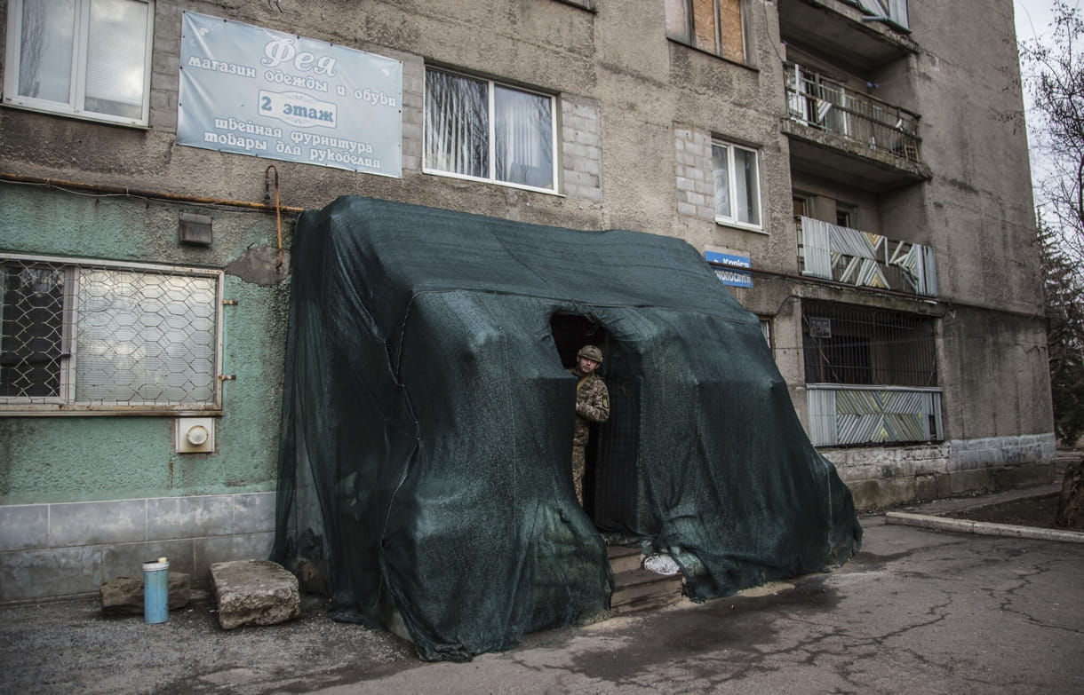 Un soldado ucraniano se asoma a un refugio en el centro del pueblo de Novoluhanske, región de Luhansk, Ucrania, el sábado 19 de febrero de 2022. (AP Photo/Oleksandr Ratushniak)