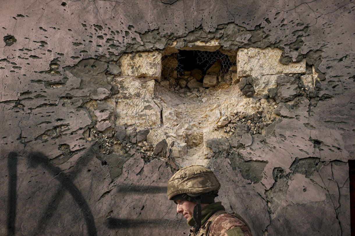Un militar ucraniano camina junto a un edificio que fue alcanzado por un proyectil de mortero de gran calibre en el pueblo de Krymske, en la región de Luhansk, en el este de Ucrania, el sábado 19 de febrero de 2022. (AP/Vadim Ghirda)