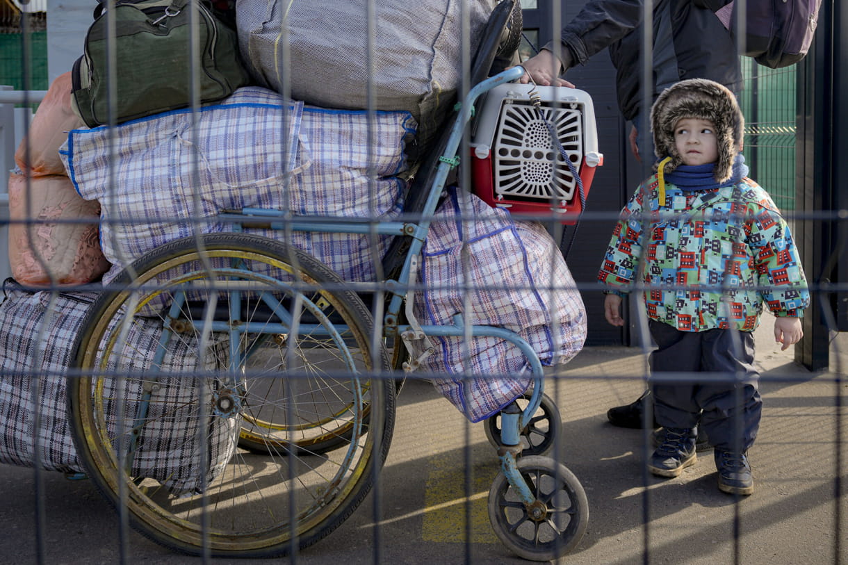 Una familia cruza desde el territorio controlado por los separatistas prorrusos a las zonas controladas por el gobierno ucraniano en Stanytsia Luhanska, el único punto de cruce abierto diariamente, en la región de Luhansk, este de Ucrania, el 22 de febrero de 2022 (AP Photo/Vadim Ghirda)