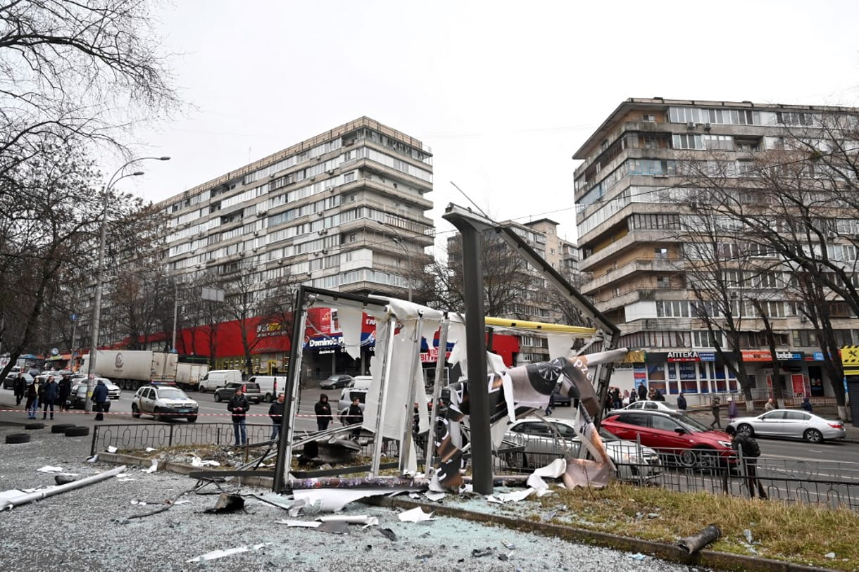 La gente se ve fuera de la zona acordonada alrededor de los restos de un proyectil en una calle de Kiev el 24 de febrero de 2022 (Sergei Supinsky / AFP)
