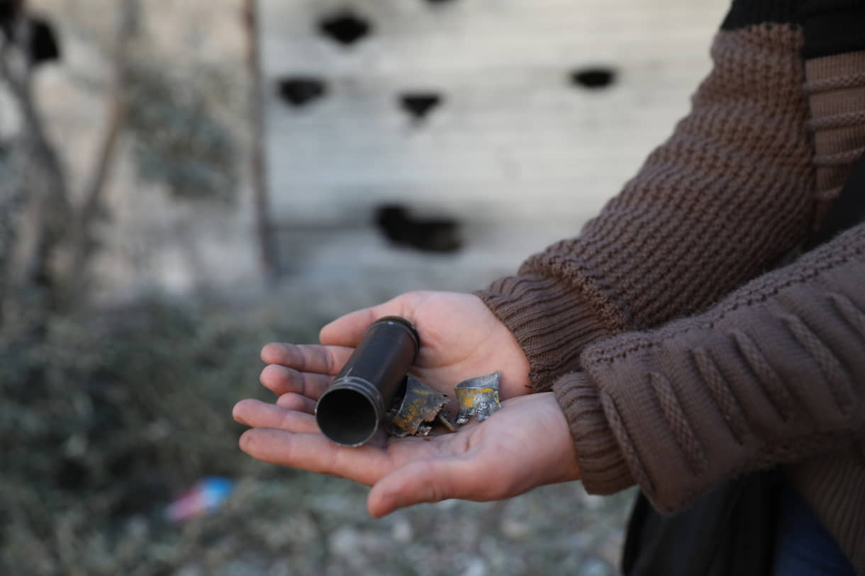 Un niño muestra un cartucho de bala vacío fuera de una casa destruida después de una operación del ejército estadounidense en el pueblo sirio de Atmeh, en la provincia de Idlib, Siria, el jueves 3 de febrero de 2022. (AP Photo/Ghaith Alsayed)