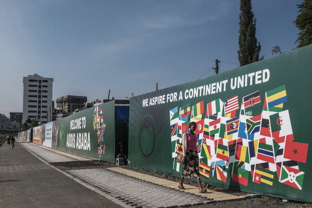 Una persona camina junto a una pancarta colocada como parte de los preparativos en la ciudad para acoger la 35ª cumbre ordinaria de la Unión Africana, en la ciudad de Addis Abeba, Etiopía, el 1 de febrero de 2022. (EDUARDO SOTERAS / AFP)